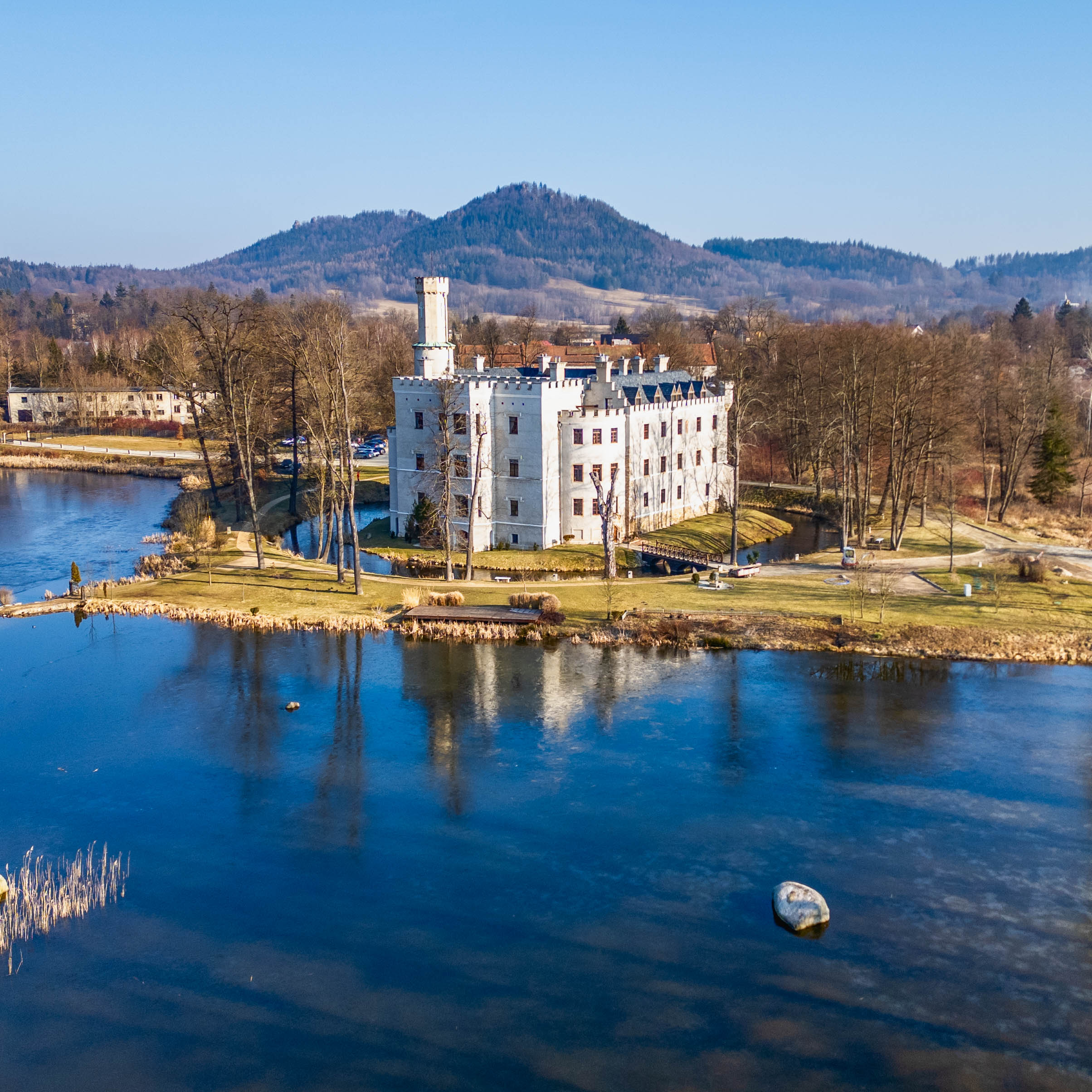 Photo du château de Karpniki prise depuis un drone – montagnes au loin.