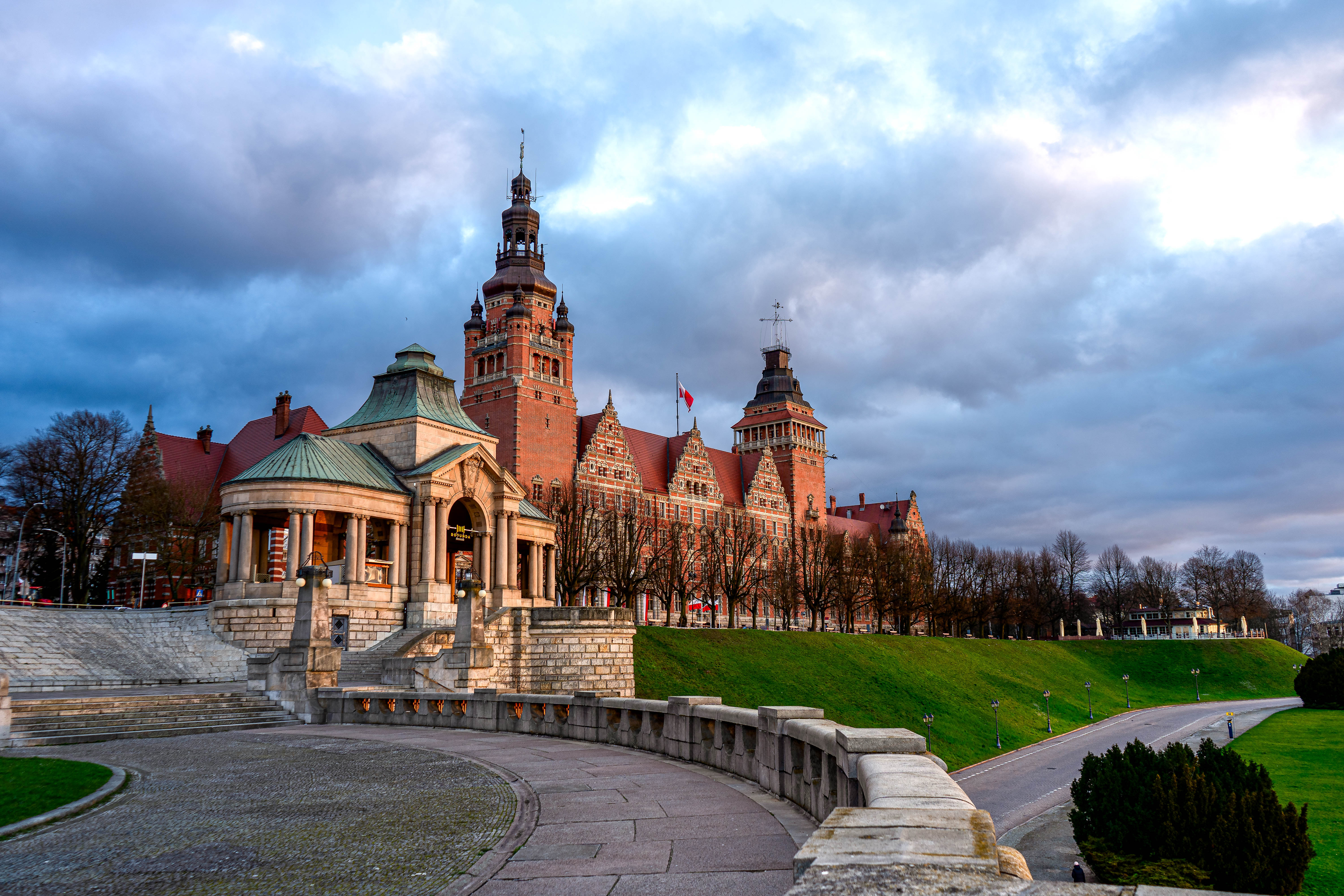Le complexe Wały Chrobrego à Szczecin, avec sa rotonde, ses marches et le bâtiment du Musée national, photographié sous un ciel dramatique dans la lumière de fin d'après-midi.